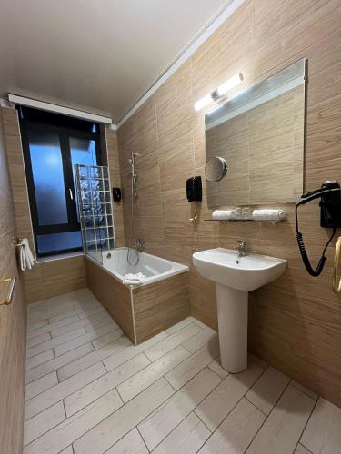une salle de bain avec une baignoire et un lavabo et une baignoire dans l'établissement Empire Hôtel, à Nîmes