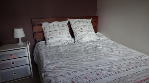 - un lit avec des draps et des oreillers blancs à côté d'une commode dans l'établissement Feel At Home Paris-Montreuil 500m Metro parking privé gratuit, à Montreuil