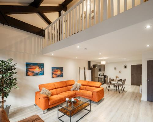 ein Wohnzimmer mit einem orangenen Sofa und einem Tisch in der Unterkunft Modern 2 Bedroom with 75” TV & Free Wi-Fi in Bradford