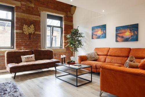 a living room with orange furniture and a brick wall at Modern 2 Bedroom with 75” TV & Free Wi-Fi in Bradford