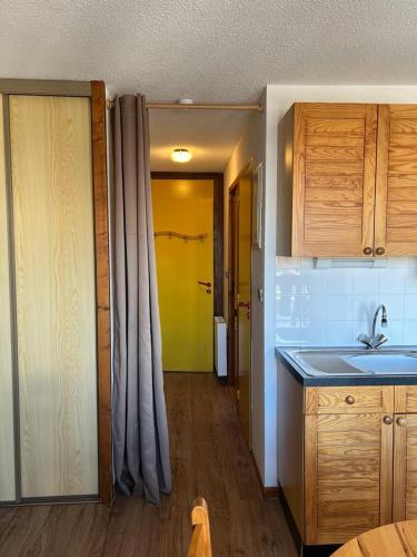 une cuisine avec un évier et une porte menant à un couloir dans l'établissement Valmeinier 1800 studio Front de neige, à Le Désert