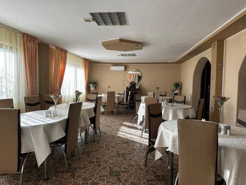 un restaurant avec tables et chaises et nappes blanches dans l'établissement Pensiunea Daiadela, à Duşeşti