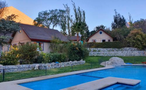 a home with a swimming pool in front of a house at Cabañas Las Gredas SPA Pisco Elqui in Pisco Elqui