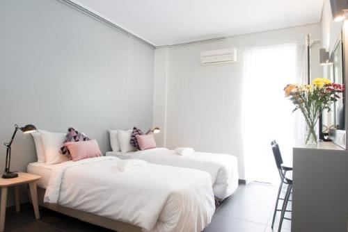 two beds in a white room with pink pillows at Athens Studios in Athens