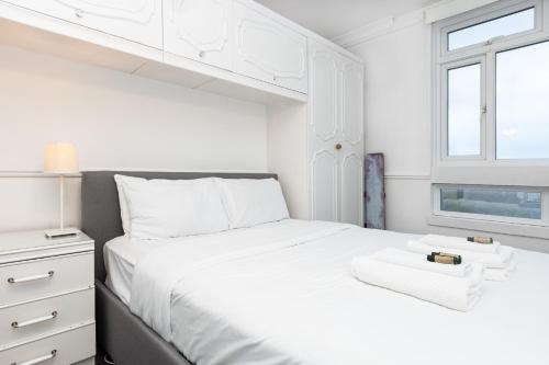 a white bedroom with a white bed and a window at Gorgeous 2BDR Flat in Shoreditch in London