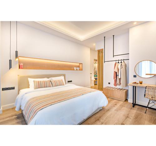 a bedroom with a large white bed and a desk at Oniro Suites in Rethymno Town