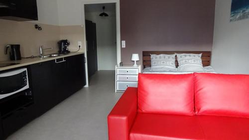 a red couch in a living room with a bed at Feel At Home Paris-Montreuil 500m Metro parking privé gratuit in Montreuil