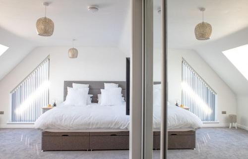 a white bedroom with a large bed and a mirror at Daisy Cottage in Eyre