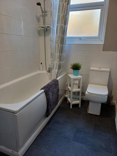 a bathroom with a white tub and a toilet at Home from Home in Faversham