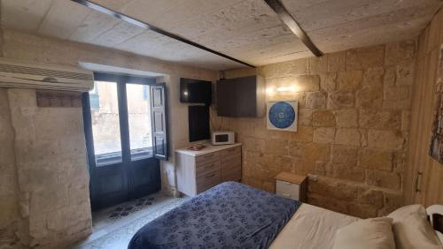 a small bedroom with a bed and a window at Servants' Quarters Studio Apartment in Valletta