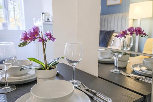 a table with wine glasses and a plant on it at Hackney Central Deluxe Apartment in London