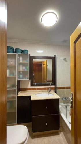 a bathroom with a sink and a toilet and a mirror at Apartamento Saudade in Cambados
