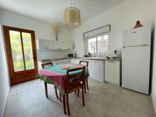 a kitchen with a table and a white refrigerator at Villa Les Oliviers proche centre Porto-Vecchio in Porto-Vecchio
