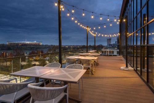 a deck with tables and lights on a building at Barceló Warsaw Powiśle in Warsaw