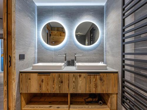 une salle de bain avec deux lavabos et deux miroirs dans l'établissement Appartement raffiné avec accès direct aux pistes, wifi et parking 2 places - FR-1-694-346, à Val dʼIsère