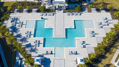 una vista aérea de una piscina con sillas y un complejo en Modern Condo with Large Outdoor Patio. Reunion Resort Water Park Access near Disney at Spectrum Resort Orlando by Rentyl - B31 #134, en Kissimmee