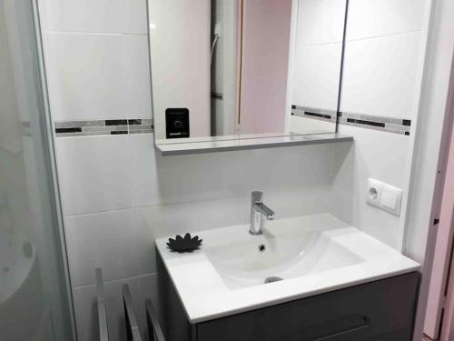 uma casa de banho branca com um lavatório e um espelho em appartement front de mer-Lop em Empuriabrava