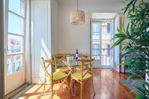 a dining room with a glass table and yellow chairs at Inglesinhos Convento 3 - Bright Apartment in Lisbon