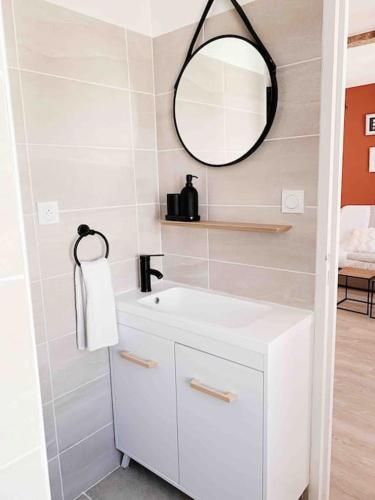 une salle de bain avec un lavabo blanc et un miroir dans l'établissement Vermeille: Terrasse calme au coeur du village, à Port-Vendres