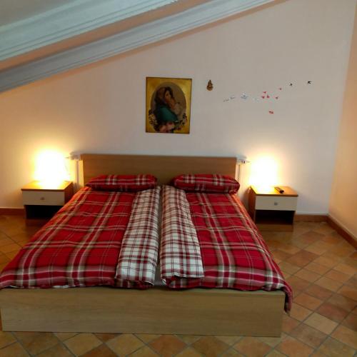 a bedroom with a bed with a red and white plaid blanket at MANSARDA VITI - Sguardo su Frontone - in Frontone