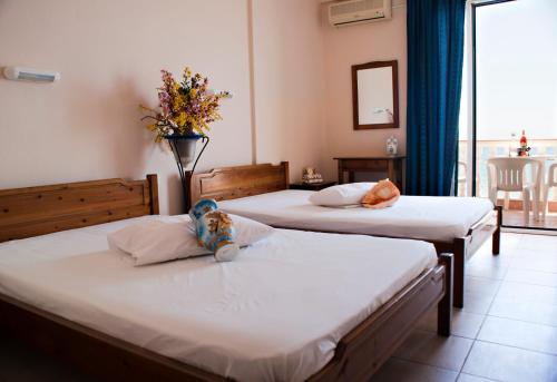 una habitación de hotel con 2 camas con un animal de peluche en la almohada en Oscar en Paralia Katerinis