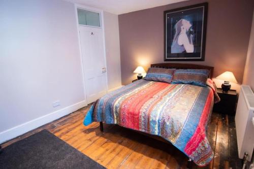 een slaapkamer met een bed met een kleurrijke deken en 2 lampen bij Fisherman's Terrace (Tardis) On Quay/Free Parking in Poole