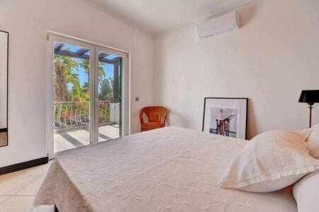 um quarto com uma cama grande e uma varanda em Villa 3 quartos piscina a 3km Vilamoura em Boliqueime