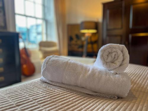 a rolled up towel sitting on top of a bed at Garnethill Charm 3 Bed Flat Central Glasgow in Glasgow