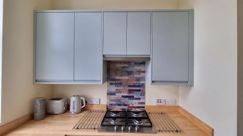 a kitchen with white cabinets and a stove at Southsea Escape - 2 double bedrooms - PARKING PERMITS INCLUDED in Portsmouth