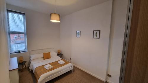 een witte slaapkamer met een bed en een raam bij Southsea Escape Coastal Apartment, 2 double bedrooms in Portsmouth