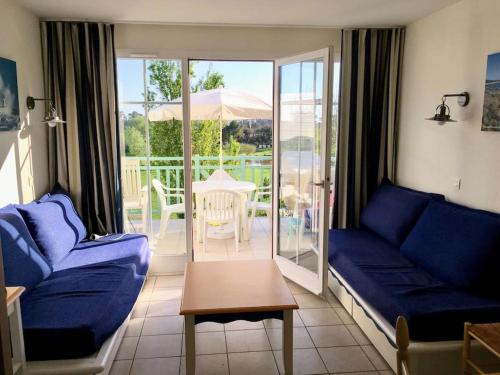 een woonkamer met een blauwe bank en een tafel bij "L'ÉVASION Ô SOLEIL" Appartement 4 personnes, vue dégagée sur le golf, accès parc aquatique gratuit in Talmont