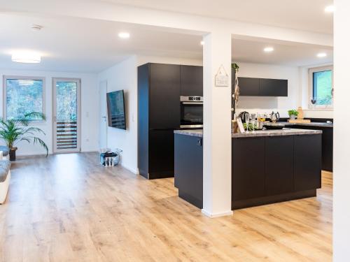 an open kitchen and living room with black cabinets at Ferienhaus Wendelinus mit Pool & Sauna in Hausach