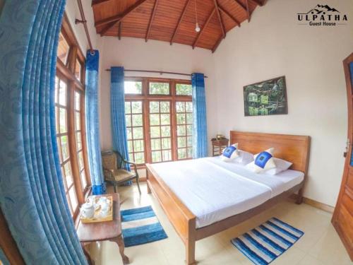 a bedroom with a bed and a large window at Ulpatha Guest House in Hatton