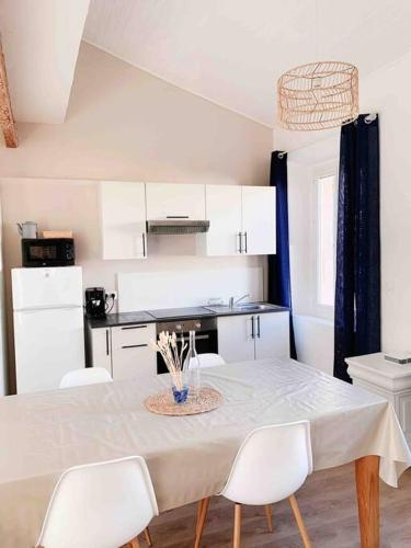 une cuisine blanche avec une table et des chaises blanches dans l'établissement Écume: Duplex lumineux au cœur du village, à Port-Vendres