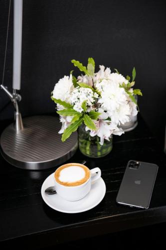 a cup of coffee on a table with a vase of flowers at Principado Downtown in Buenos Aires