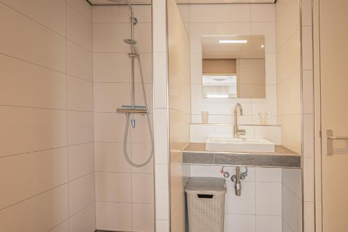 La salle de bains est pourvue d'une douche et d'un lavabo. dans l'établissement Appartementencomplex Juliana 128, à De Koog