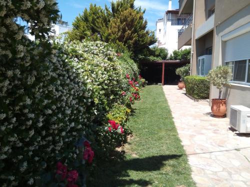 a hedge of flowers in a yard next to a building at Avenue Luxury Apartments in Alexandroupoli