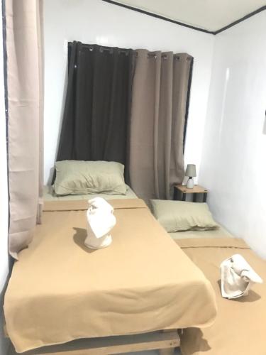 two beds in a room with a window at Central Hub Homestay in Puerto Princesa City