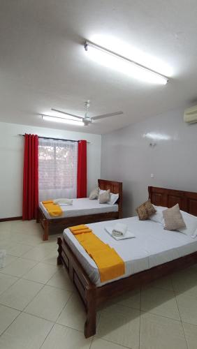 2 Betten in einem Zimmer mit roten Vorhängen in der Unterkunft Baraka Suites, Nyali Gulf Links Apartment by Gash Homestays C-1 in Mombasa