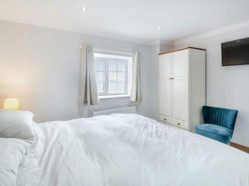 um quarto com uma cama branca e uma cadeira azul em Mylo’s Cottage - Langrick, Lincolnshire em Boston