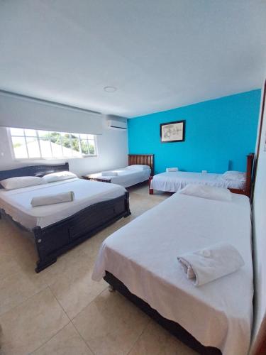 a room with three beds and a blue wall at Hotel Sierra Nevada B&B SAS in Valledupar