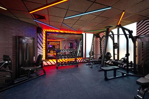 un gimnasio con equipamiento cardiovascular y sillas en una habitación en NYX Hotel Dublin Portobello, en Dublín