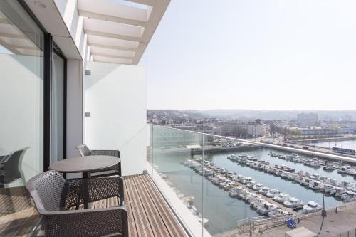 a balcony with a table and chairs and a harbor at Evancy La Marina Boulogne-sur-Mer in Boulogne-sur-Mer