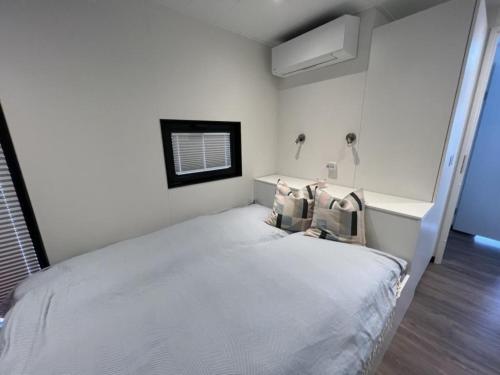 a white bedroom with a large white bed with pillows at Hausboot Bakerman in Zehdenick