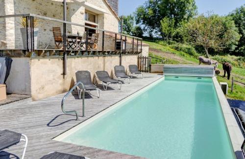 een zwembad op een terras met stoelen en een huis bij Le Petit Paradis in Saint-Pompain