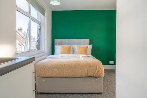 a bedroom with a green wall and a bed at KHAFAJI INN in East Barnet