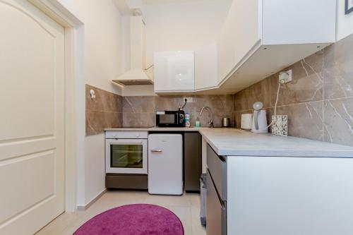 een kleine keuken met witte kasten en een paars tapijt bij I.K.Apartments in Boedapest