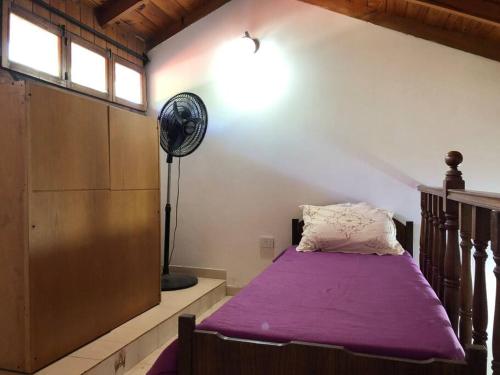 Cette chambre comprend un lit avec des draps violets et un ventilateur. dans l'établissement Casa Santa Clara del Mar, à Santa Clara del Mar