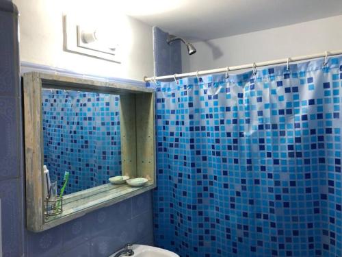 La salle de bains est pourvue d'une douche carrelée de bleu et d'un miroir. dans l'établissement Casa Santa Clara del Mar, à Santa Clara del Mar