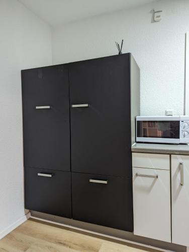 une armoire noire dans une cuisine équipée d'un four micro-ondes dans l'établissement Ferienwohnung nahe Europa Park, à Lahr/Schwarzwald